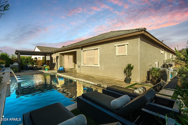 back house at dusk with pool water feature and a patio area