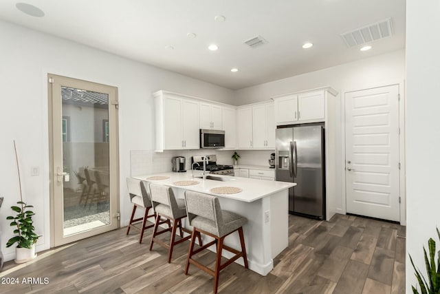 kitchen featuring a kitchen breakfast bar, white cabinetry, dark hardwood / wood-style flooring, and appliances with stainless steel finishes