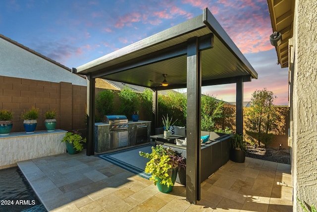 patio terrace at dusk featuring grilling area, area for grilling, and ceiling fan