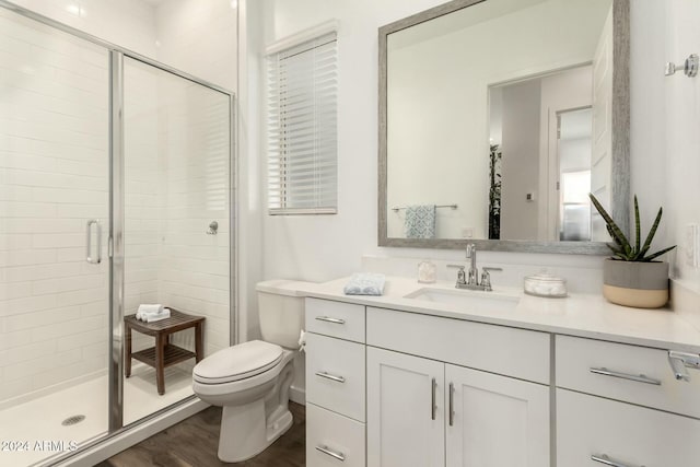 bathroom with wood-type flooring, vanity, toilet, and a shower with door