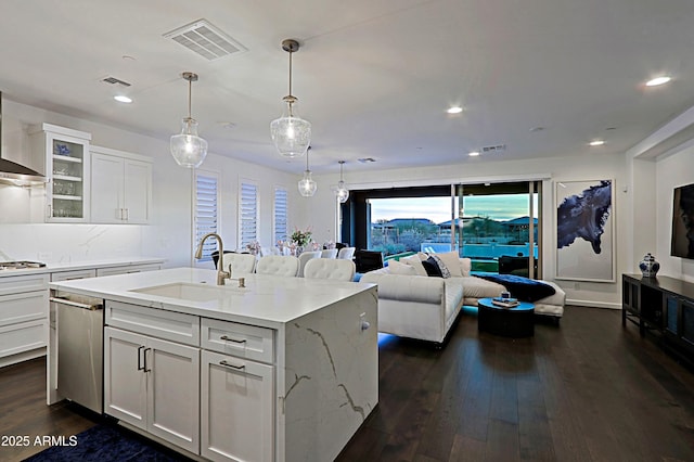 kitchen featuring sink, dark hardwood / wood-style floors, light stone counters, an island with sink, and white cabinets