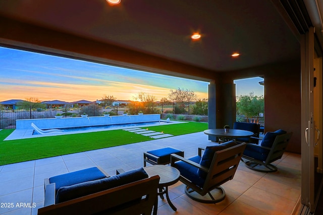 patio terrace at dusk with a pool and a lawn