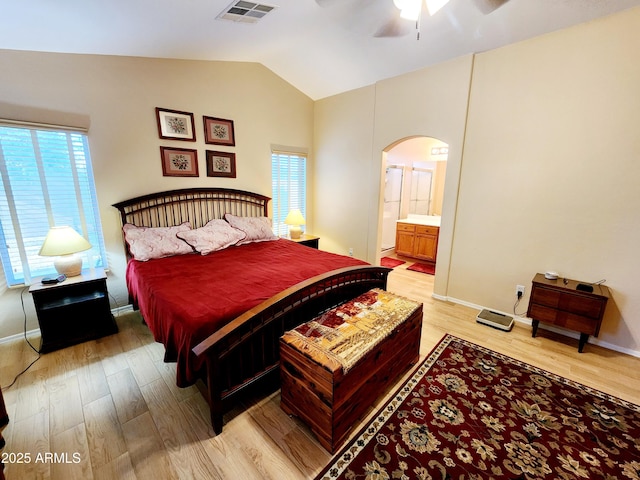 bedroom featuring ceiling fan, connected bathroom, vaulted ceiling, and light wood-type flooring