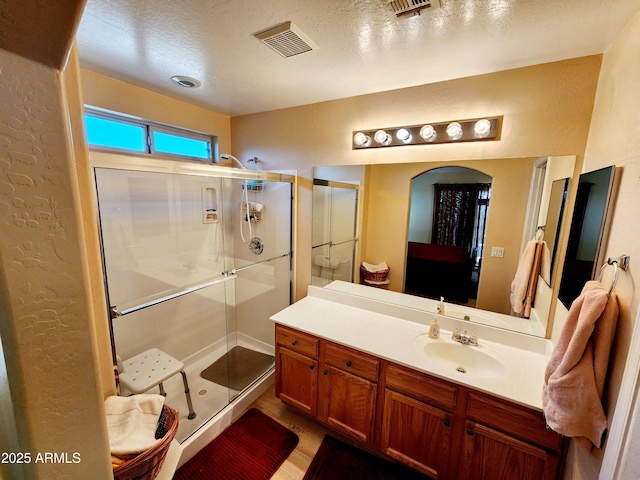 bathroom featuring vanity, hardwood / wood-style floors, a textured ceiling, and a shower with shower door