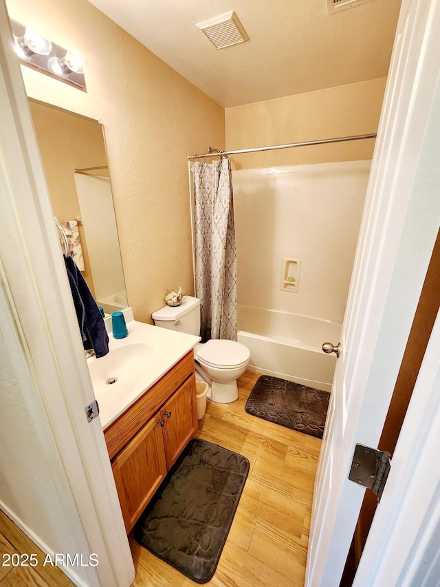 full bathroom featuring vanity, hardwood / wood-style floors, shower / bath combination with curtain, and toilet