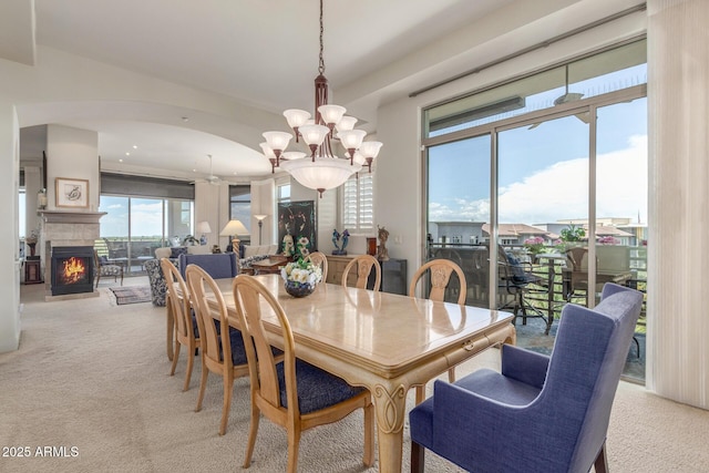 dining room with a lit fireplace, light colored carpet, a chandelier, and recessed lighting