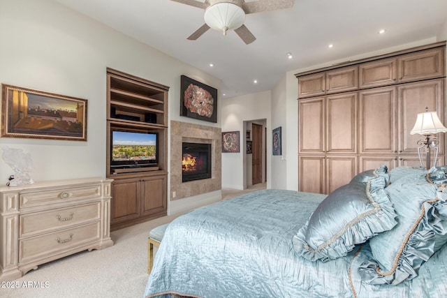 bedroom with a closet, recessed lighting, ceiling fan, light carpet, and a tiled fireplace