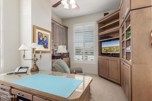 office area featuring light carpet, baseboards, and a ceiling fan