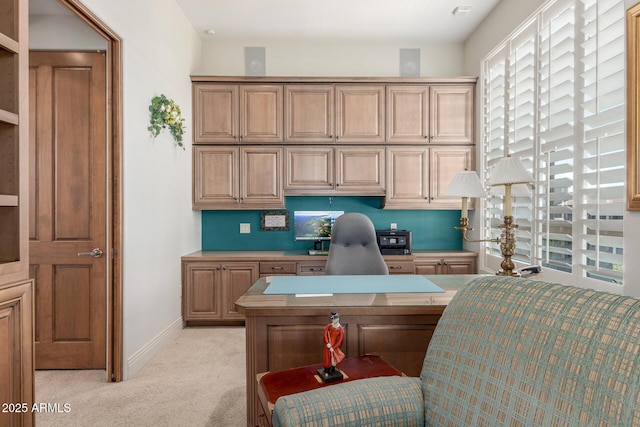 home office with light colored carpet, built in study area, and baseboards