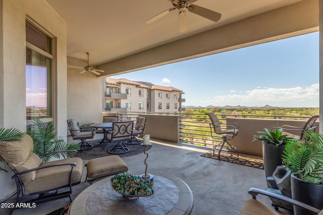 view of patio featuring a balcony, outdoor dining area, ceiling fan, and a mountain view