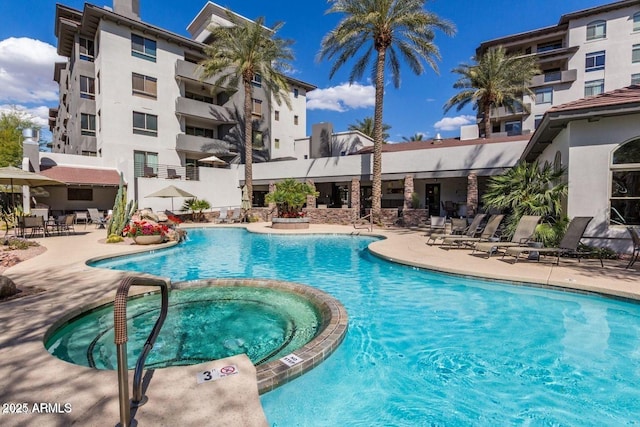 pool with a hot tub and a patio
