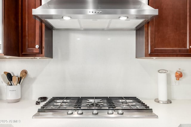 room details featuring stainless steel gas stovetop and wall chimney exhaust hood