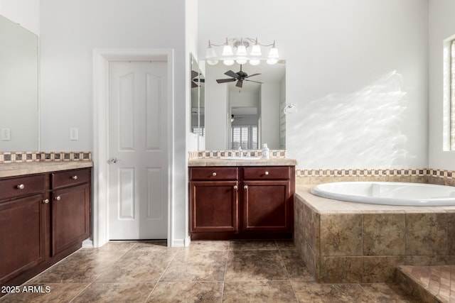 bathroom with ceiling fan, vanity, and a relaxing tiled tub