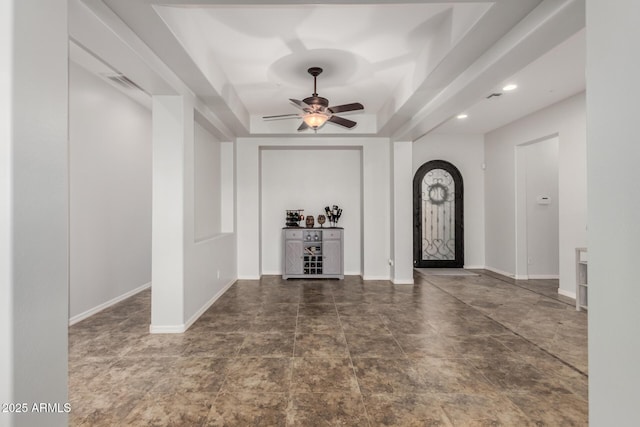 foyer featuring a raised ceiling and ceiling fan