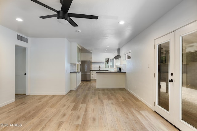 kitchen with stainless steel refrigerator, french doors, light hardwood / wood-style flooring, white cabinets, and wall chimney exhaust hood