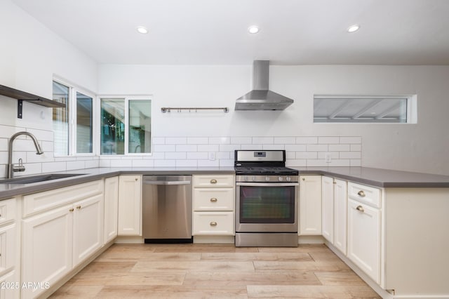 kitchen featuring appliances with stainless steel finishes, sink, decorative backsplash, and wall chimney exhaust hood