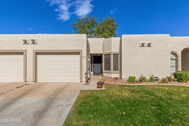 view of front facade with driveway, a garage, a front yard, and stucco siding