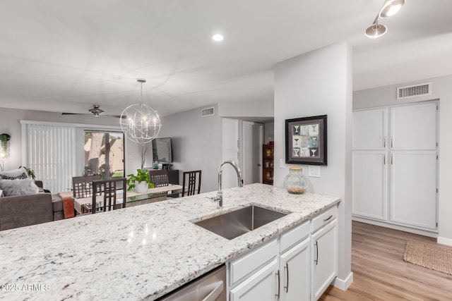 kitchen featuring white cabinetry, visible vents, open floor plan, and a sink