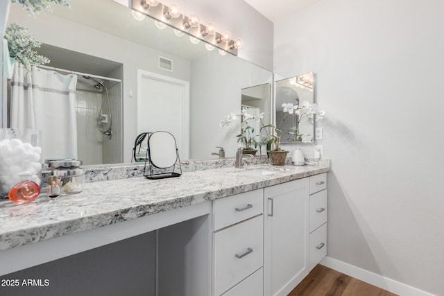 full bath with curtained shower, wood finished floors, vanity, visible vents, and baseboards