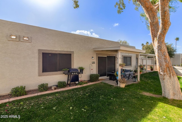 exterior space featuring a patio area, a yard, and stucco siding