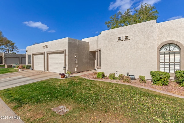 pueblo-style house with driveway, a front lawn, an attached garage, and stucco siding