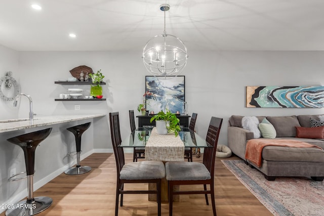 dining area with an inviting chandelier, baseboards, wood finished floors, and recessed lighting