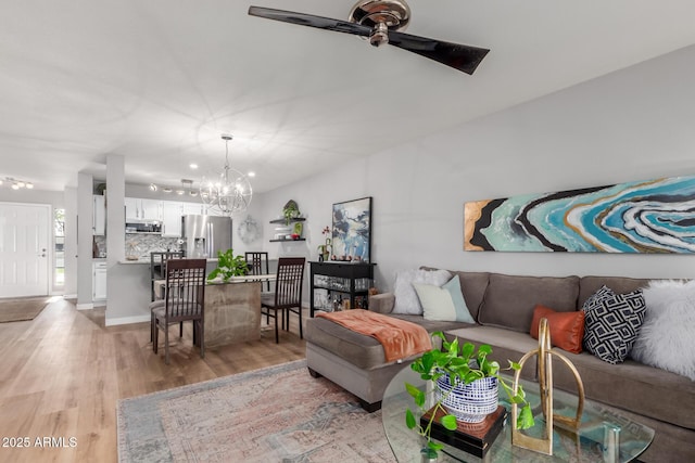 living room featuring light wood finished floors and ceiling fan with notable chandelier