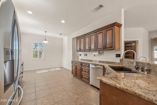 kitchen with light stone counters, sink, stainless steel appliances, and hanging light fixtures