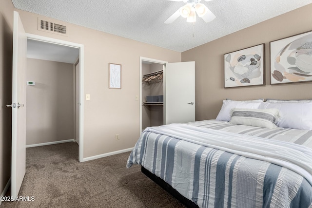 bedroom featuring visible vents, a textured ceiling, carpet, baseboards, and a spacious closet