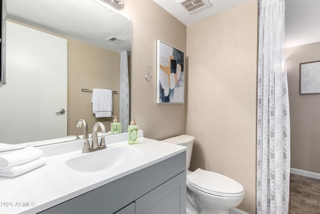 bathroom featuring visible vents, toilet, and vanity