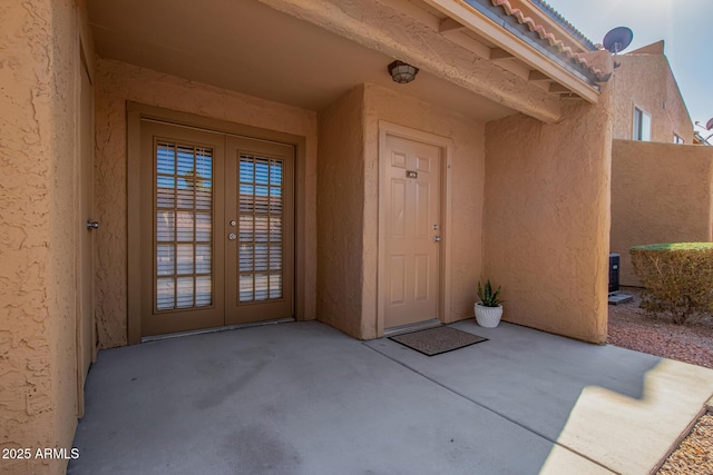 view of exterior entry with a patio area, stucco siding, and french doors