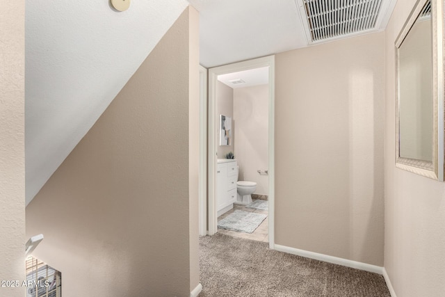 corridor featuring baseboards, visible vents, and carpet floors