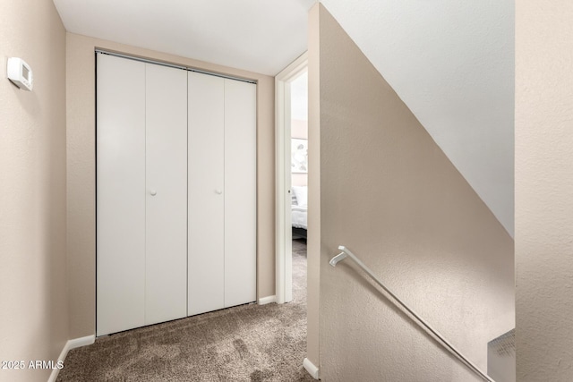 corridor with baseboards, carpet flooring, and a textured wall