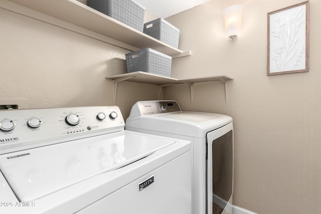 laundry area with laundry area, washing machine and dryer, and a textured wall