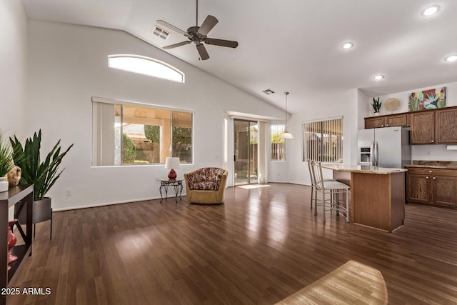 kitchen with stainless steel fridge, dark hardwood / wood-style flooring, a kitchen island, and hanging light fixtures