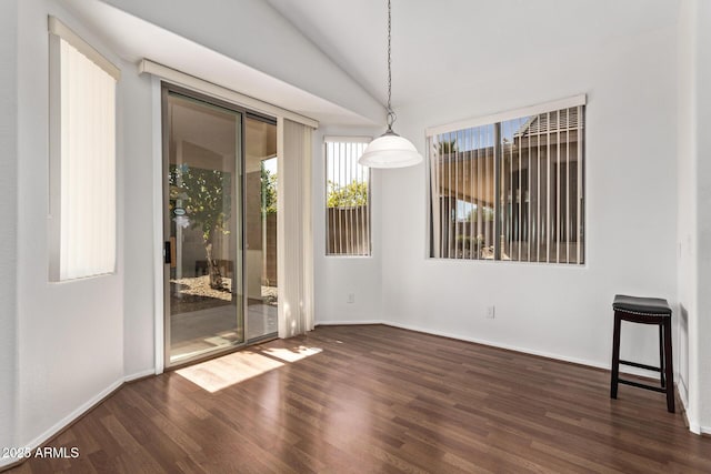 unfurnished dining area featuring dark wood-type flooring and lofted ceiling