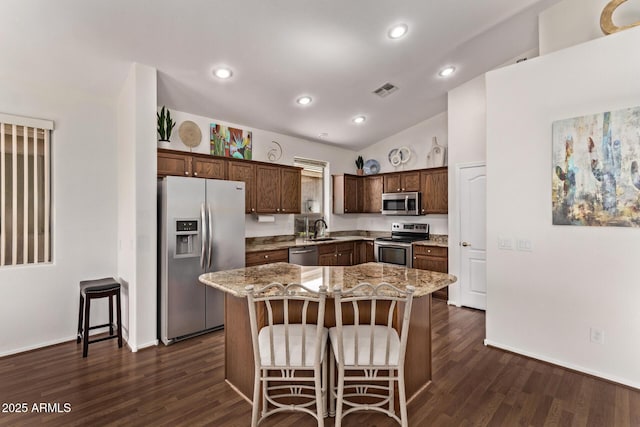 kitchen featuring appliances with stainless steel finishes, a kitchen bar, a kitchen island, sink, and lofted ceiling