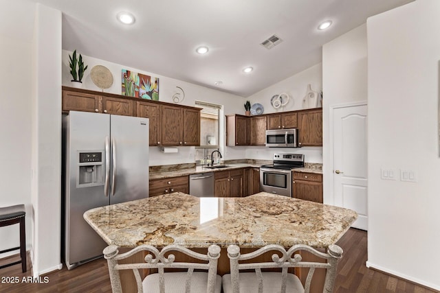 kitchen featuring stainless steel appliances, dark hardwood / wood-style flooring, a center island, and light stone counters