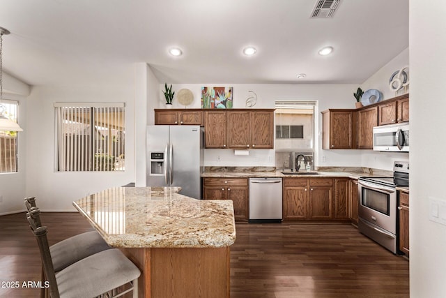 kitchen featuring sink, dark hardwood / wood-style floors, a kitchen island, a breakfast bar, and appliances with stainless steel finishes