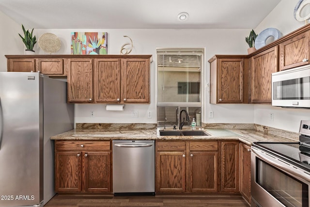 kitchen featuring sink, dark hardwood / wood-style floors, light stone counters, and appliances with stainless steel finishes