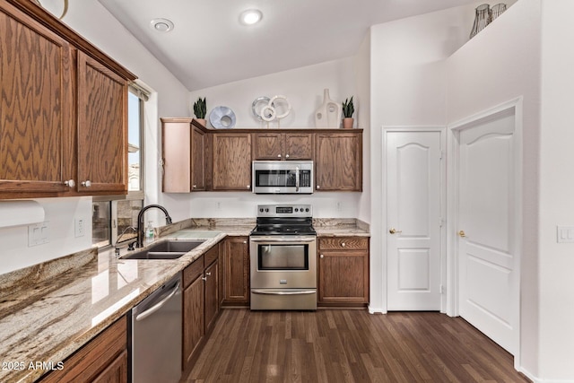 kitchen featuring light stone countertops, vaulted ceiling, dark hardwood / wood-style floors, stainless steel appliances, and sink