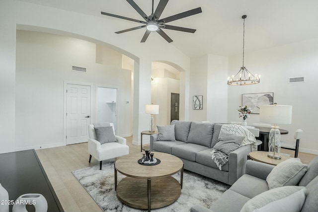 living area featuring light wood finished floors, visible vents, and arched walkways