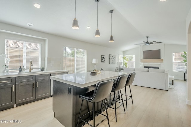 kitchen with lofted ceiling, light countertops, a fireplace, and light wood-style flooring