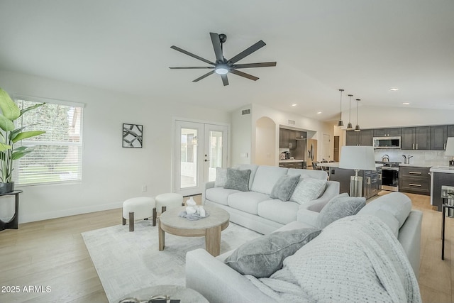 living room featuring arched walkways, french doors, light wood finished floors, lofted ceiling, and recessed lighting