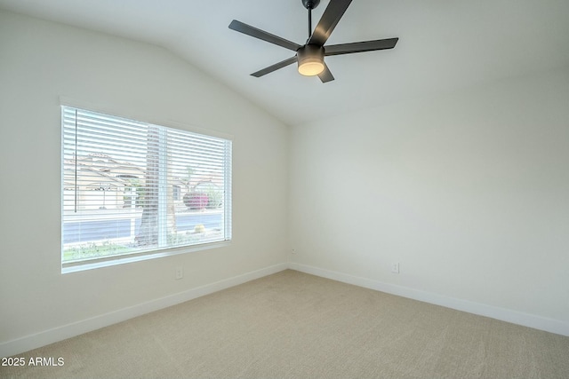 carpeted spare room featuring lofted ceiling, ceiling fan, and baseboards