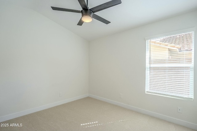 spare room with baseboards, ceiling fan, and light colored carpet