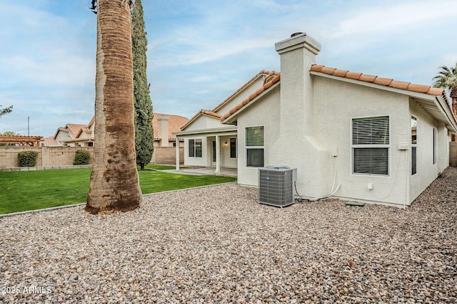 back of property featuring cooling unit, fence, a lawn, stucco siding, and a patio area