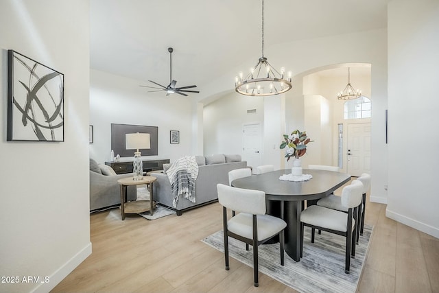 dining space featuring light wood-style flooring, baseboards, and ceiling fan with notable chandelier