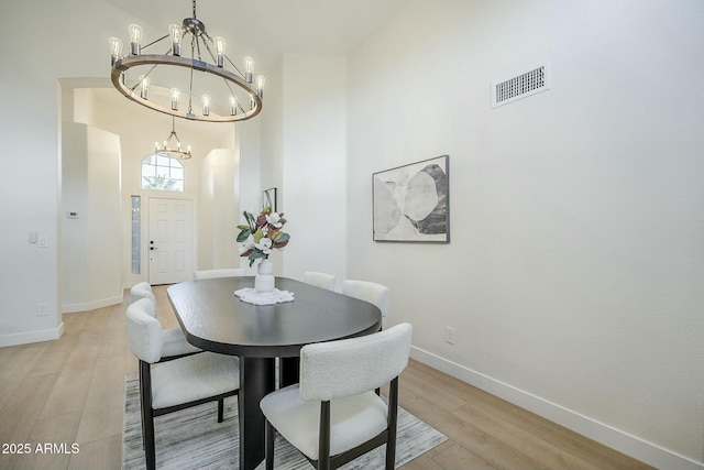 dining room featuring baseboards, light wood-style floors, visible vents, and an inviting chandelier