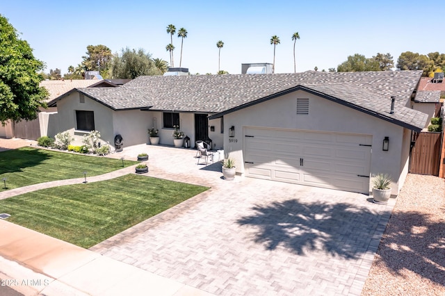 ranch-style home with fence, decorative driveway, a garage, stucco siding, and a front yard